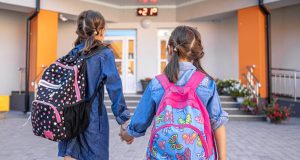 Calendario escolar de Madrid 2026-2027 con todos los puentes y vacaciones Dos niñas con mochila entrando de la mano en el colegio